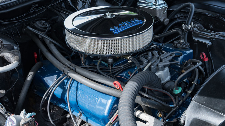 A closeup of a Ford 351 V8 with blue valve covers and a chrome air cleaner
