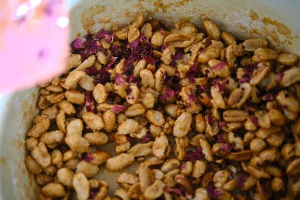Peanuts in a saucepan with sugar and dried rose petals